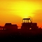 Illustration: A tractor with no driver working the field at sunset.