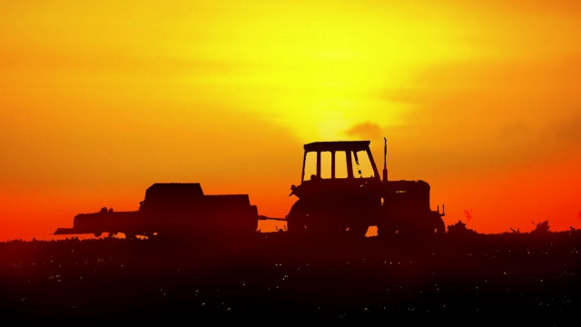 Illustration: A tractor with no driver working the field at sunset.